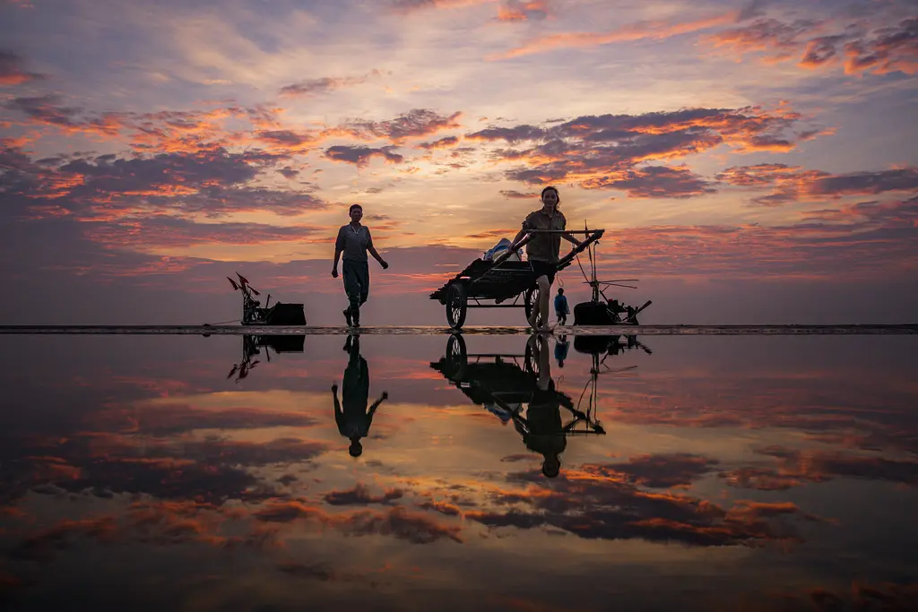 Compress PNG, before: two people pulling a cart across a mirror-wet beach at sunset, PNG, 1.8 MB