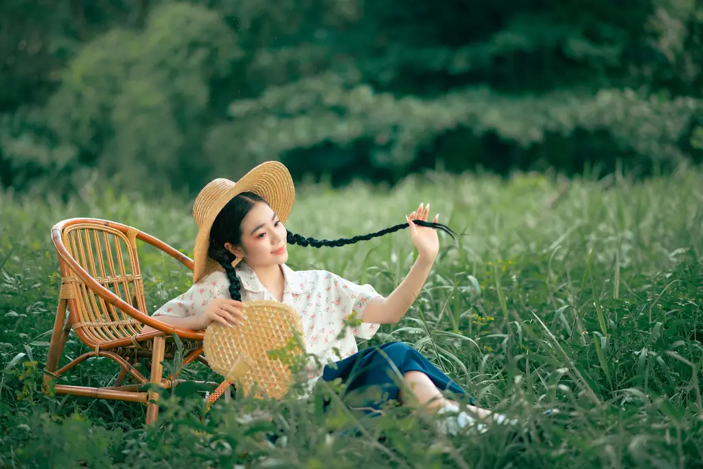 PNG to AVIF converter, before: a woman in a straw hat lounging on a rattan chair in a green meadow, PNG, 1.7 MB