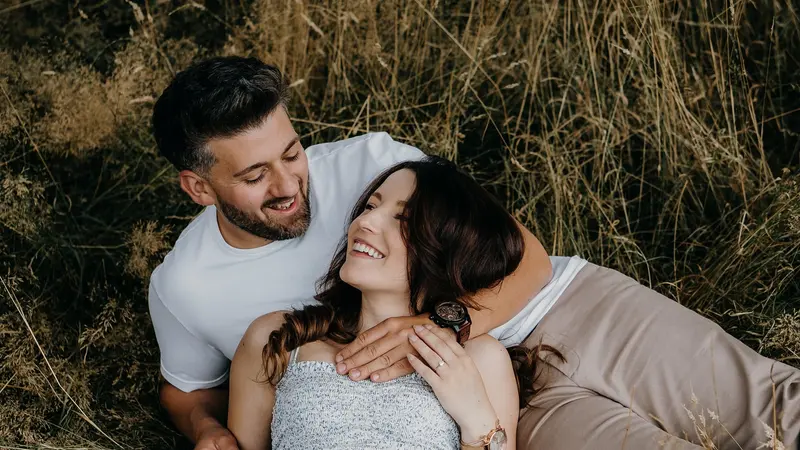 A laughing couple lying together in dry golden grass