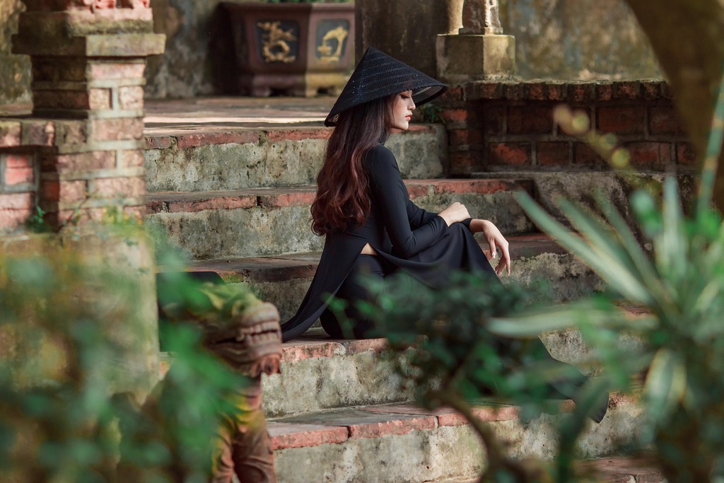 Rotate image online, before: a woman in black with a conical hat sitting on old temple steps, Original, 174.9 KB